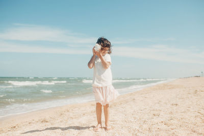 Woman standing at beach against sky