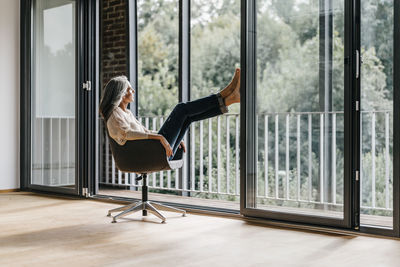 Woman with long grey hair sitting on chair at the window