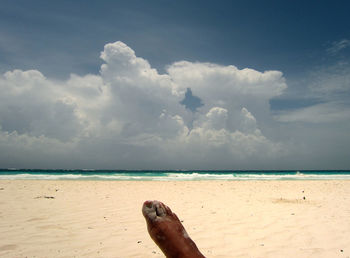 Low section of woman at beach against sky