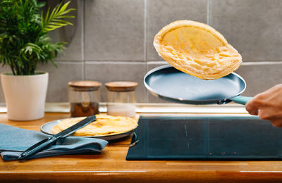 Midsection of person cooking pancakes in pan on kitchen counter