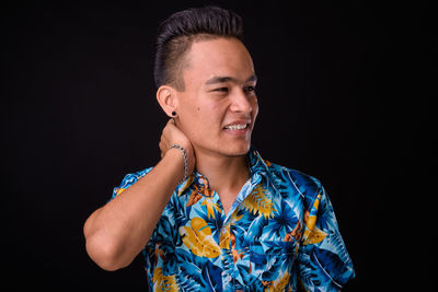 Portrait of young man looking away against black background