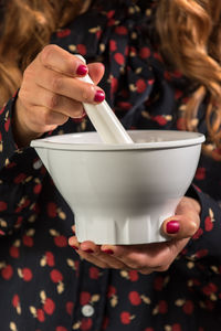 Midsection of woman holding mortar and pestle