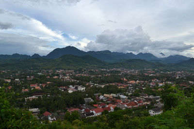 Aerial view of townscape by mountains against sky