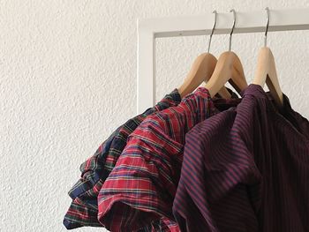 Close-up of shirts hanging on coathangers by wall