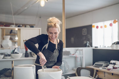 Smiling woman mixing paint in workshop