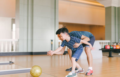 Full length of father playing with son at bowling alley