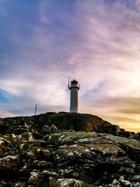 Low angle view of lighthouse by buildings against sky