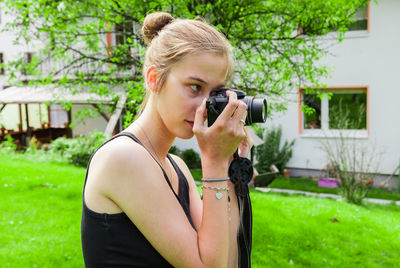 Young woman photographing while standing on grass