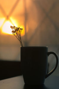 Close-up of coffee cup on table at sunset