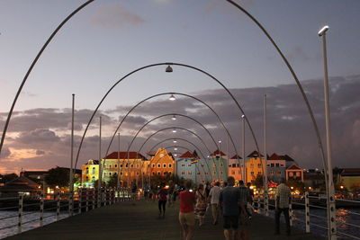 Group of people walking on illuminated street amidst buildings in city