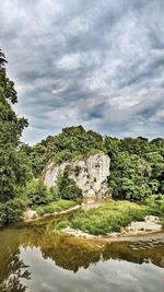 Scenic view of rocks by trees against sky