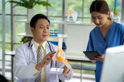 Portrait of young man using digital tablet while standing in office