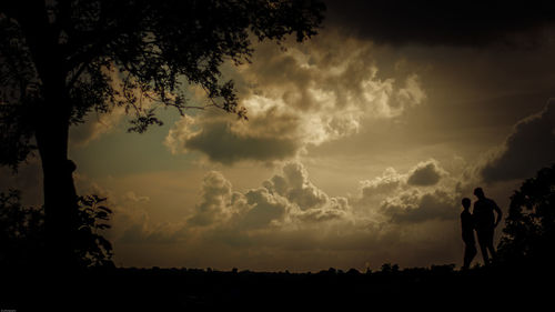 Silhouette people standing on landscape against sky during sunset