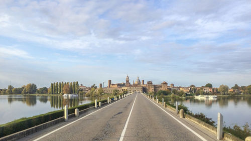 View of city at waterfront against cloudy sky