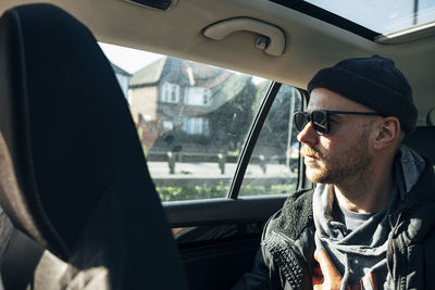 Young man wearing sunglasses sitting in car