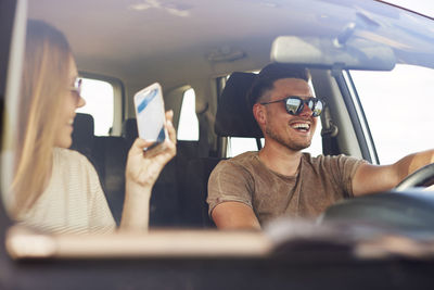 Woman photographing man in car