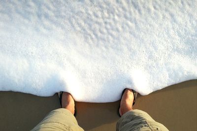 Low section of man standing on sea shore