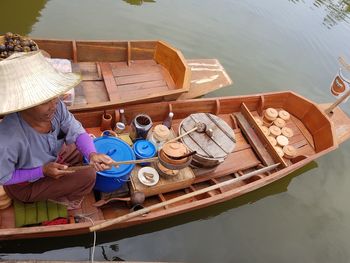High angle view of smiling senior woman selling food on boat in lake