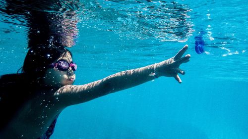 Girl reaching for bottle cap while swimming in pool