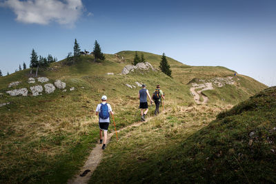 Rear view of men walking on trail against sky