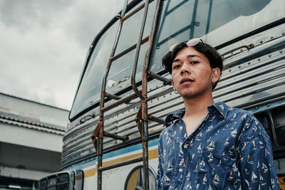 Young man standing by bus