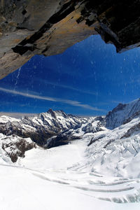 Scenic view of snowcapped mountains against blue sky