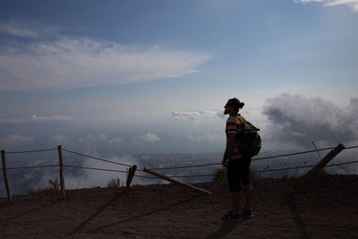 Rear view of woman standing on railing against sea