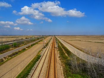 Railroad track amidst field against sky