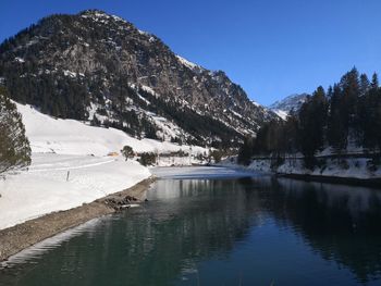 Scenic view of lake by snowcapped mountains against sky