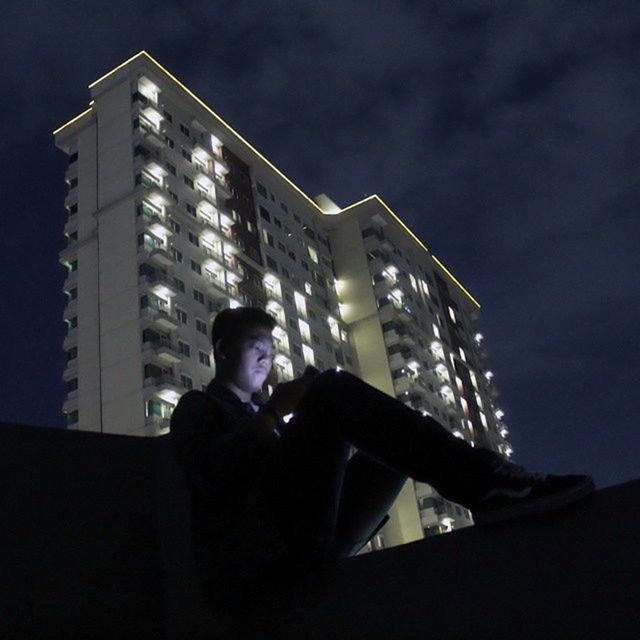 lifestyles, leisure activity, built structure, architecture, young adult, night, young men, headshot, low angle view, building exterior, sky, waist up, photographing, photography themes, side view, men, person, sitting
