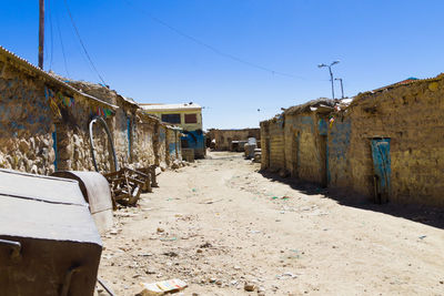 Empty road amidst buildings against clear blue sky