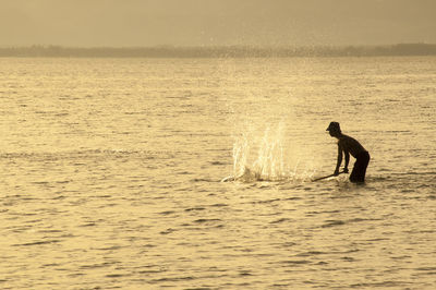 Silhouette fisherman fishing in sea