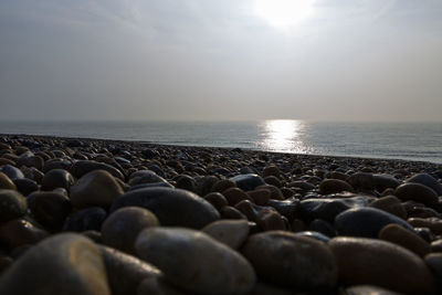 Pebbles on beach against sky during sunset