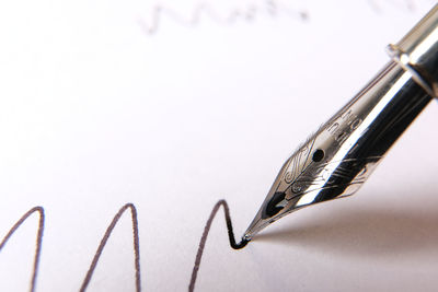 Close-up of pen on paper against white background