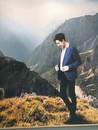 Young man standing on mountain against lake