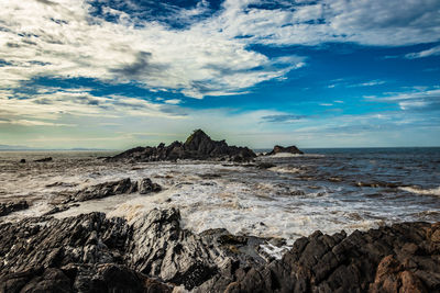 Rocky sea beach with crashing waves at morning from flat angle