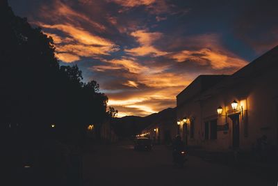 Illuminated street against sky at night