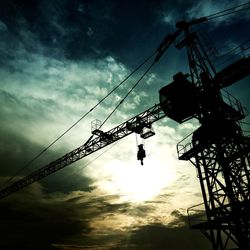 Low angle view of silhouette cranes against sky at sunset