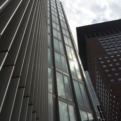 Low angle view of modern building against cloudy sky