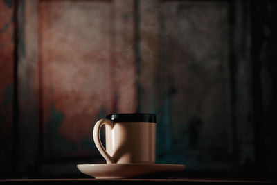 Close-up of coffee cup on table against wall