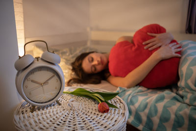 Low section of woman with alarm clock on sofa at home