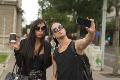 Young couple taking selfie on street through mobile phone