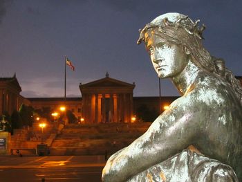Statue in city against sky at night