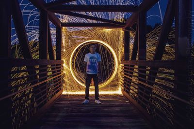 Full length of woman standing on illuminated bridge at night
