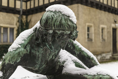 Snow covered statue by building