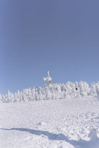 Snow covered land against clear blue sky