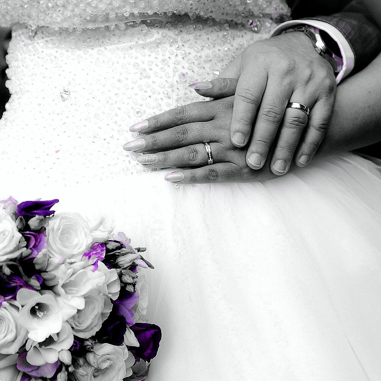 CLOSE-UP OF COUPLE HOLDING HANDS WITH FLOWERS