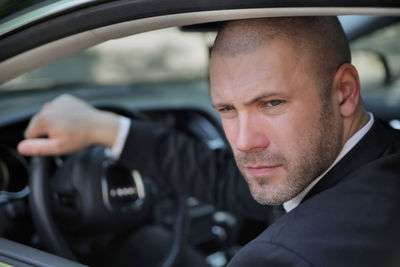 Portrait of confident businessman driving car