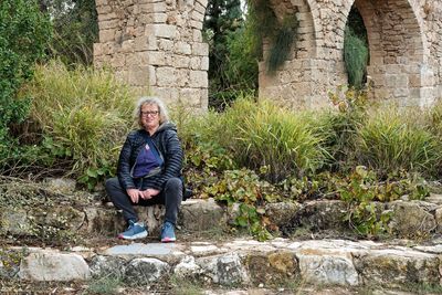 Portrait of a woman sitting against wall