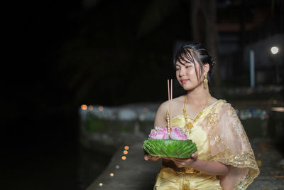 Portrait of young woman standing in city at night